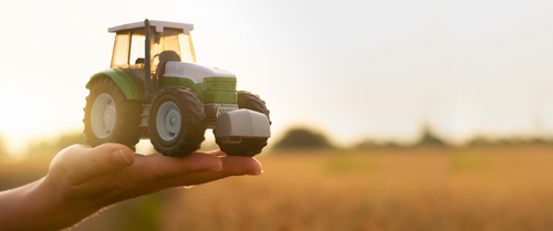 Woman,farmer,holds,a,toy,tractor,on,a,background,of