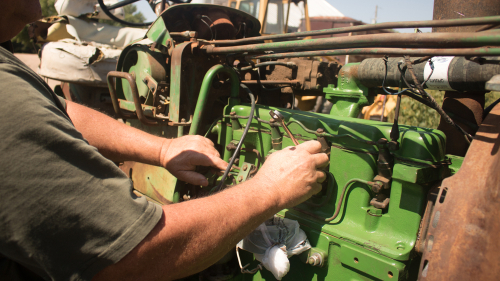 Close,up,of,agricultural,mechanic,working,on,an,antique,green